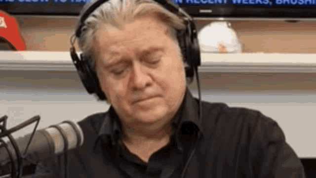 a man wearing headphones is crying while sitting in front of a microphone .
