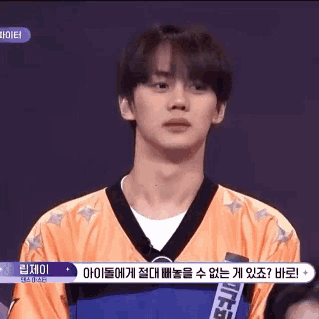 a young man is standing in front of a purple background wearing a yellow and black jersey .