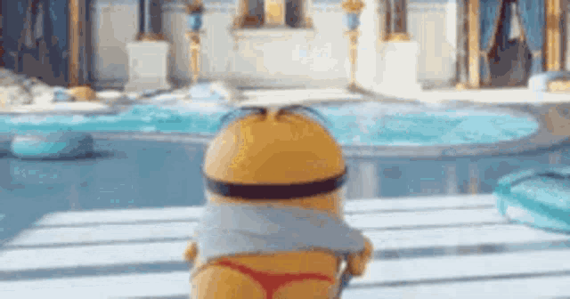 a minion is standing in front of a swimming pool wearing a bikini bottom .
