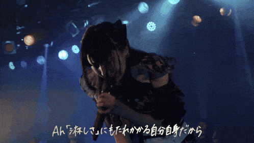 a woman singing into a microphone with chinese writing on the bottom right