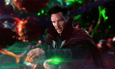 doctor strange is wearing a red cape and holding a green object in his hand .