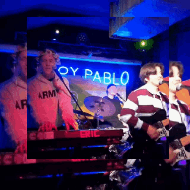 a man in an army shirt sings into a microphone on stage