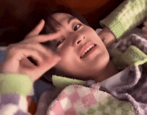 a close up of a person laying on a bed with a blanket on their face .