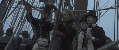 a group of men are standing on a ship and one of them has a badge on his chest that says ' a '