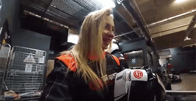 a woman in a racing suit is holding a helmet in her hands .