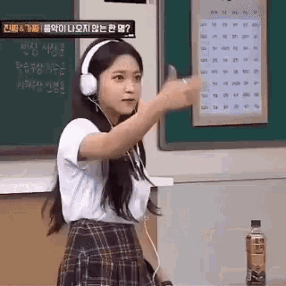 a woman wearing headphones and a plaid skirt is standing in a classroom .
