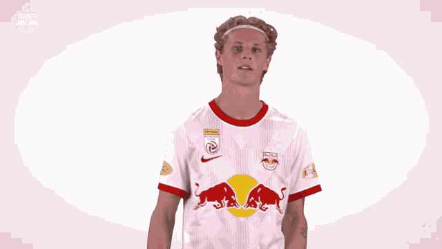 a man wearing a red bull jersey holds his arms up in the air