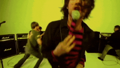 a man sings into a microphone in front of a marshall amplifier