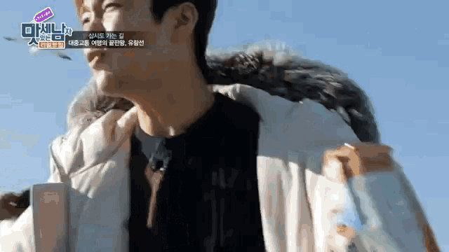 a man wearing a white jacket with a fur collar is walking .