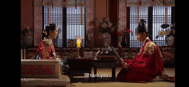 a man in a red costume is kneeling down next to a woman in a green costume and says thank you