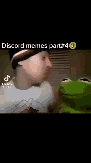 a man is talking to a kermit the frog while wearing a beanie .
