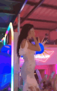 a woman in a white dress is dancing in a room with balloons .