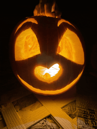 a pumpkin with a face carved into it sits on a piece of plywood that says react