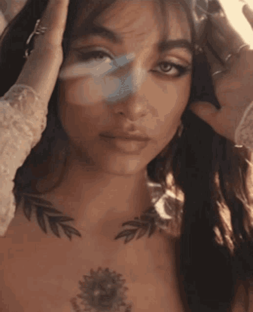 a woman with a tattoo on her chest holds her hand to her face
