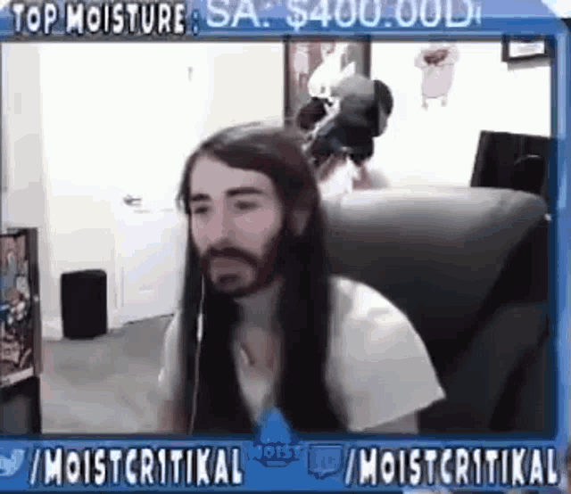 a man with long hair and a beard is sitting in a chair on a computer screen .