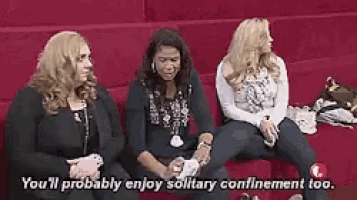 three women are sitting on a red couch and one of them is talking .