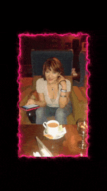 a woman sitting in a chair with a cup of coffee and a cell phone