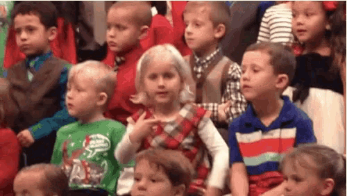 a group of children are sitting in a row watching a performance