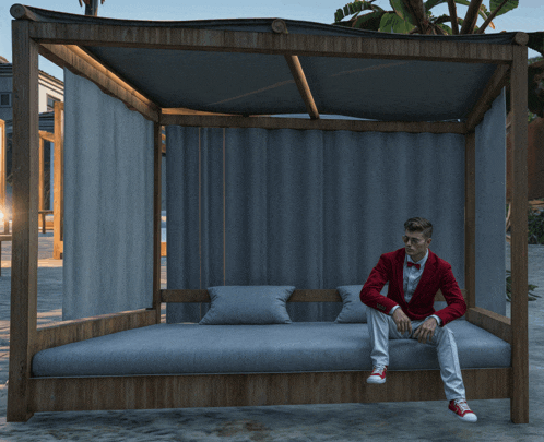 a man in a red jacket sits on a bed