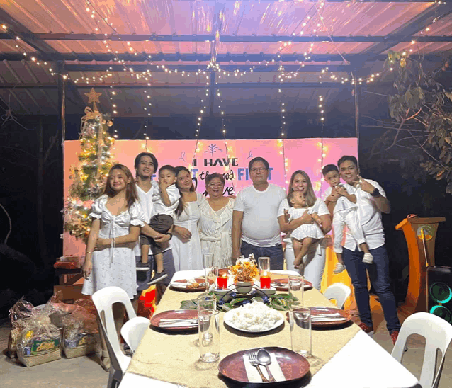 a family posing for a picture in front of a sign that says " i have a the first "
