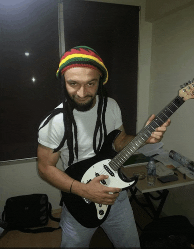 a man with dreadlocks is holding a guitar in his hands