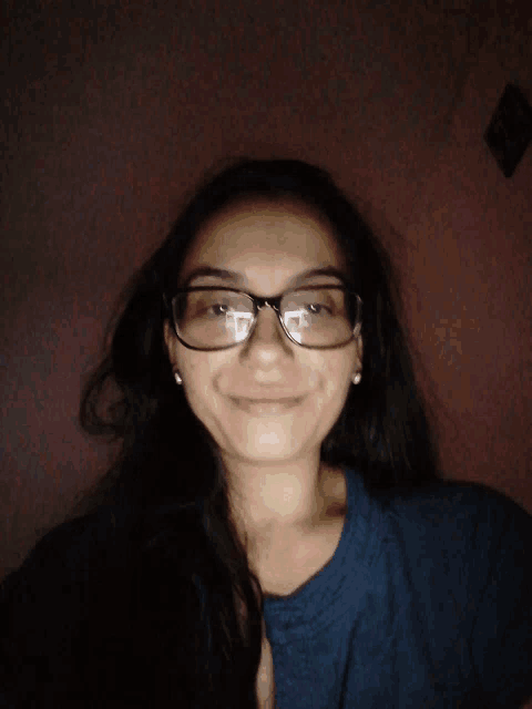 a woman wearing glasses and earrings smiles for the camera