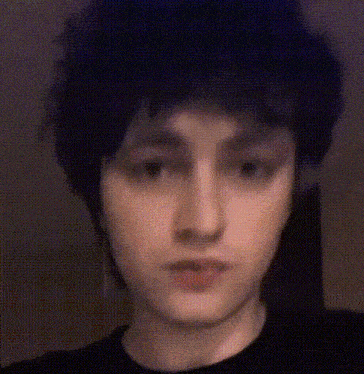 a close up of a person 's face with black hair and a black shirt .
