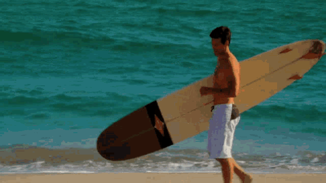 a man carrying a surfboard with a diamond on it