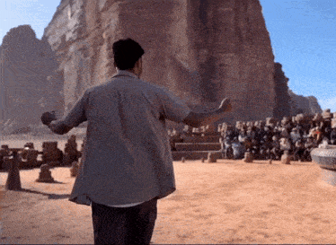 a man in a white shirt is standing in the desert