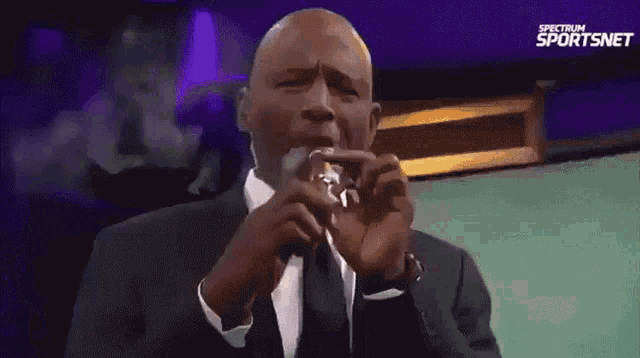 a man in a suit and tie is smoking a cigar in front of a spectrum sportsnet banner