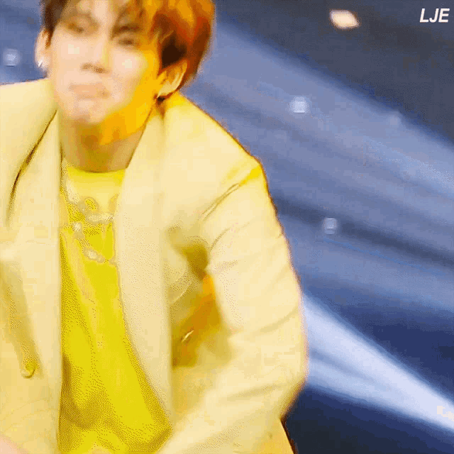 a blurry picture of a man in a yellow jacket and yellow shirt with the letters lje on the bottom