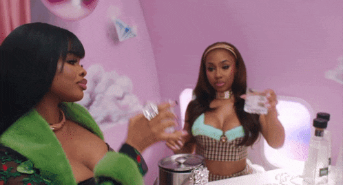 two women standing next to each other with one holding a glass