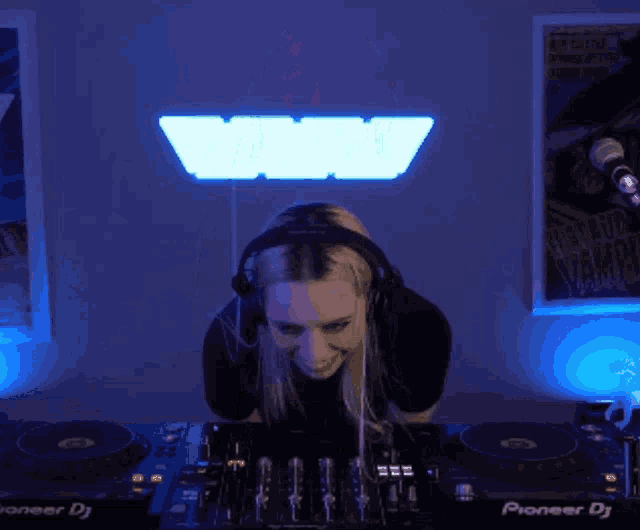 a woman wearing headphones playing music on pioneer dj equipment