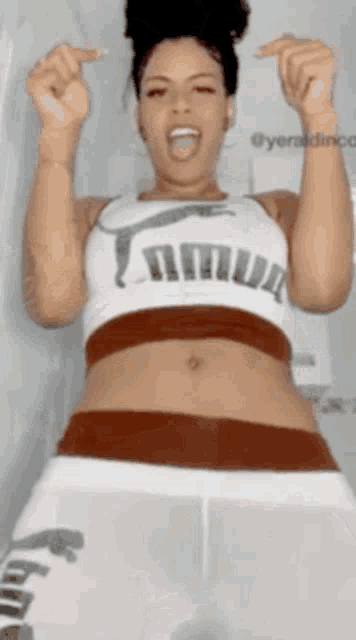 a woman wearing a crop top with the word puma on it is making a funny face .