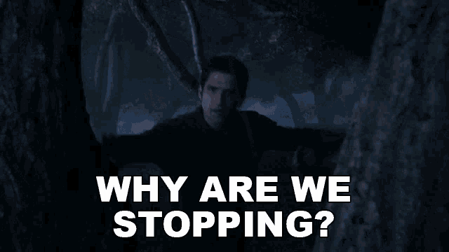 two men are standing next to each other in a dark room and one of them is asking why are we stopping .