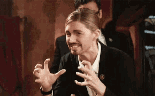 a man with a beard and mustache is making a funny face while sitting at a table .