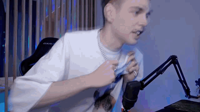 a man sitting in front of a microphone with the word dxr on his shirt