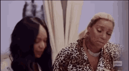 two women in leopard print shirts are sitting next to each other in a room .