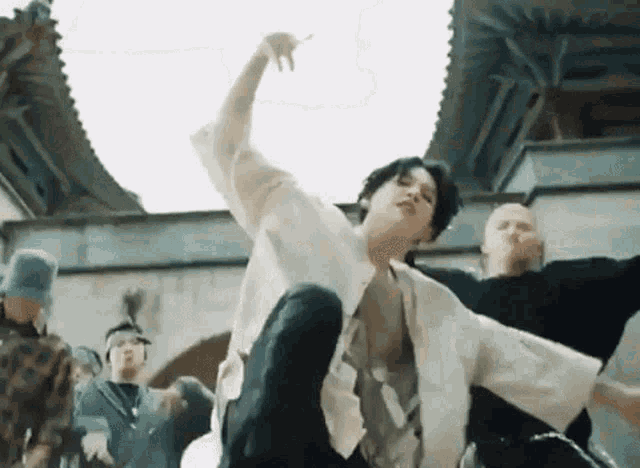 a group of people are dancing in a room with a man sitting on the floor .