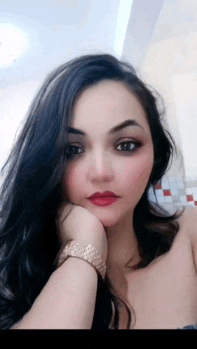 a woman wearing a watch and red lipstick looks at the camera