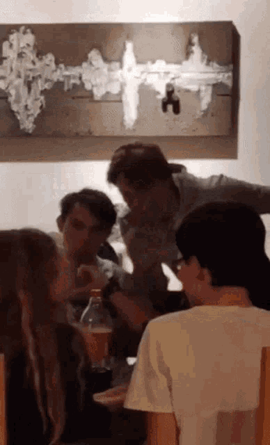 a group of people sitting at a table with a painting on the wall