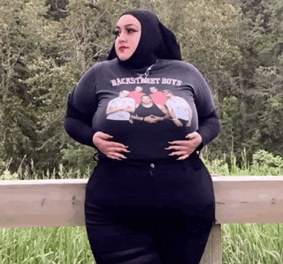 a woman wearing a backstreet boys shirt is leaning on a railing