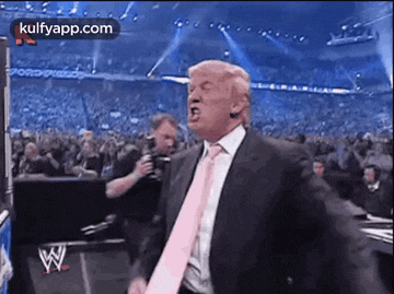 a man in a suit and pink tie is dancing in front of a crowd .