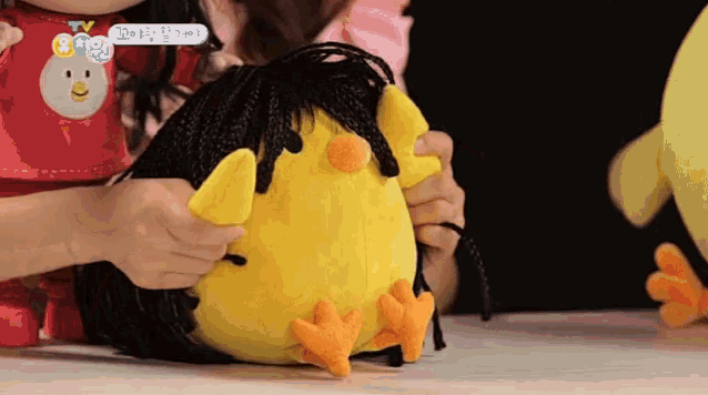 a stuffed chicken with braided hair is being played with by a child