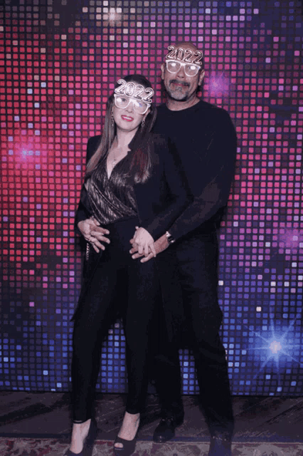 a man and woman are posing for a picture with glasses that say 2022 on them