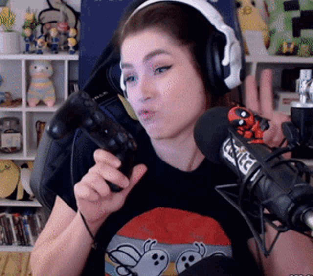 a woman wearing headphones holds a game controller in front of a microphone that says tntc on it