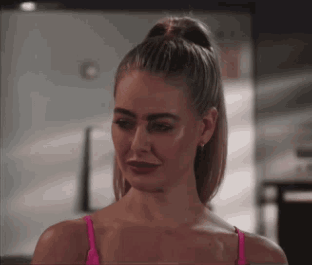 a woman with her hair in a ponytail looks at the camera