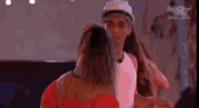 a man and a woman are dancing together in a room . the woman is wearing a hard hat .