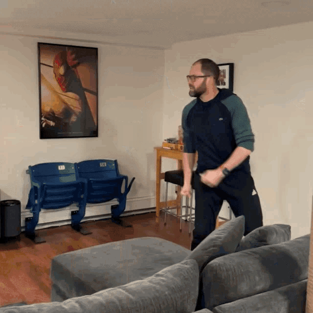 a man is dancing in a living room with a poster of spider man on the wall