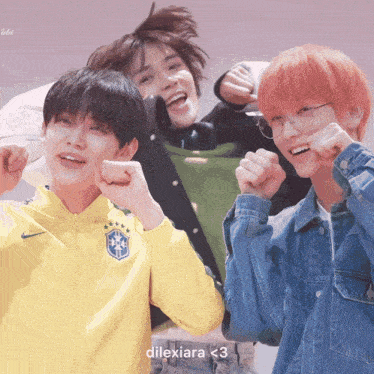 three young men are posing for a picture and one of them is wearing a yellow jacket with a soccer ball on it